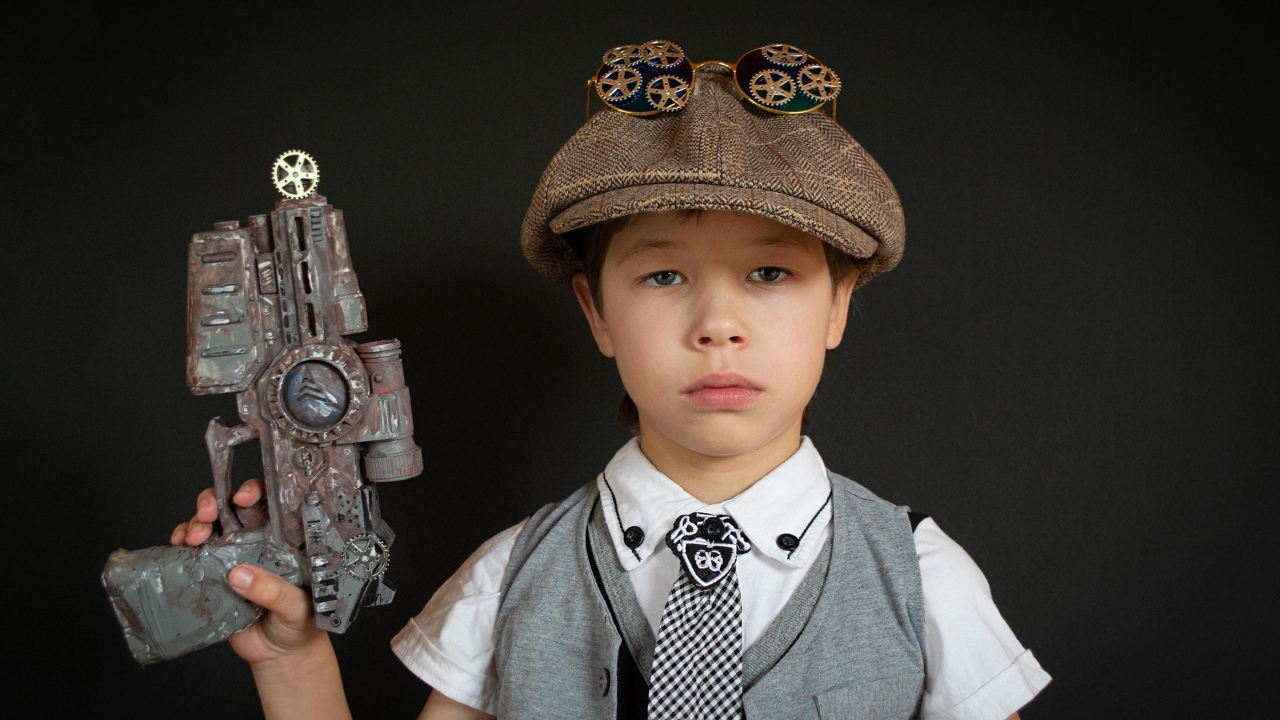 Маленький мальчик с игрушечным пистолетом на черном фоне