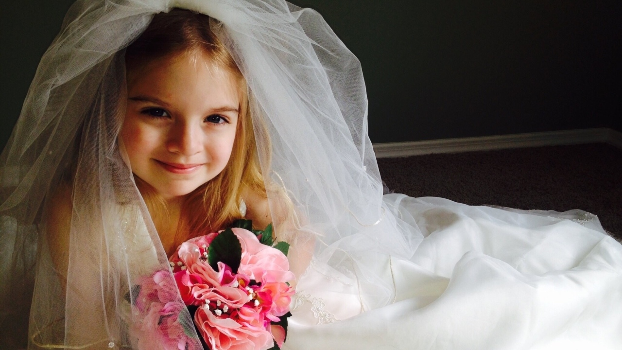 Маленькая девочка в костюме невесты с букетом