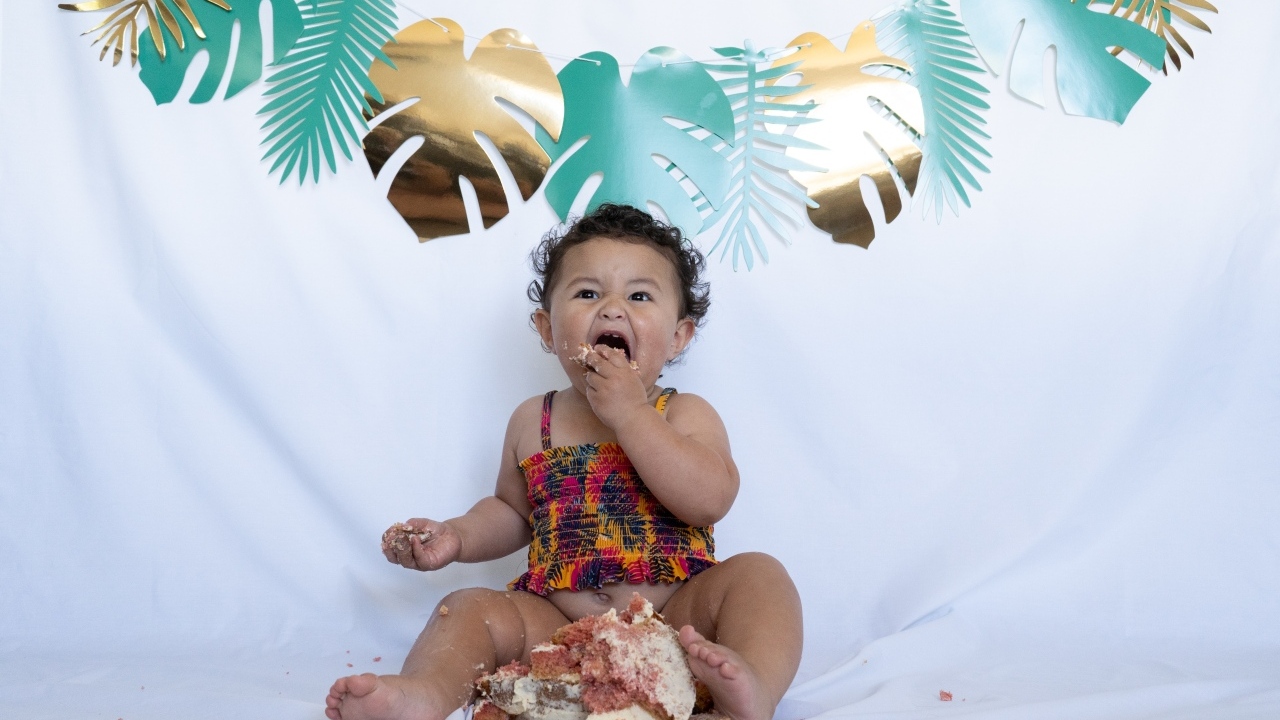 Маленькая девочка ест торт на белом фоне