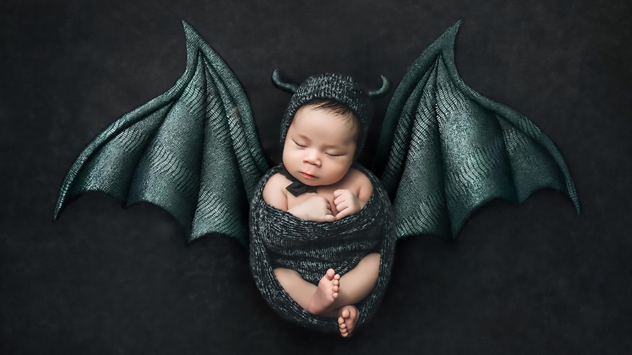 Маленький спящий ребенок с крыльями на Хэллоуин