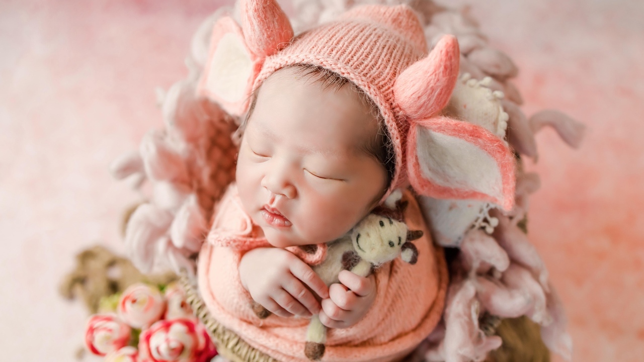 Маленький спящий новорожденный ребенок в шапке с рогами