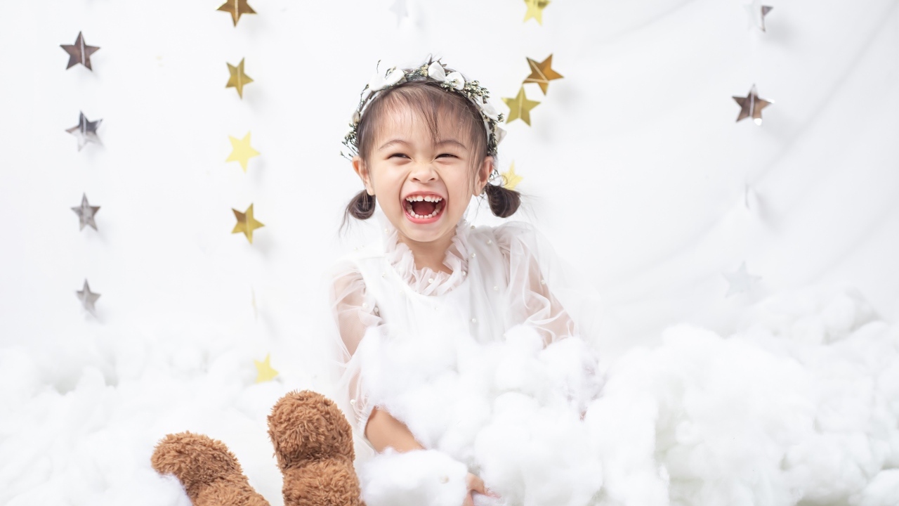 Маленькая улыбающаяся девочка азиатка в белом платье