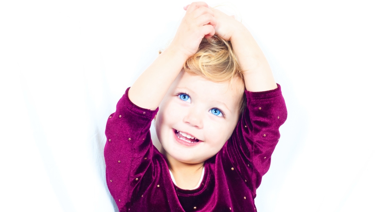 Маленькая улыбающаяся голубоглазая девочка на белом фоне