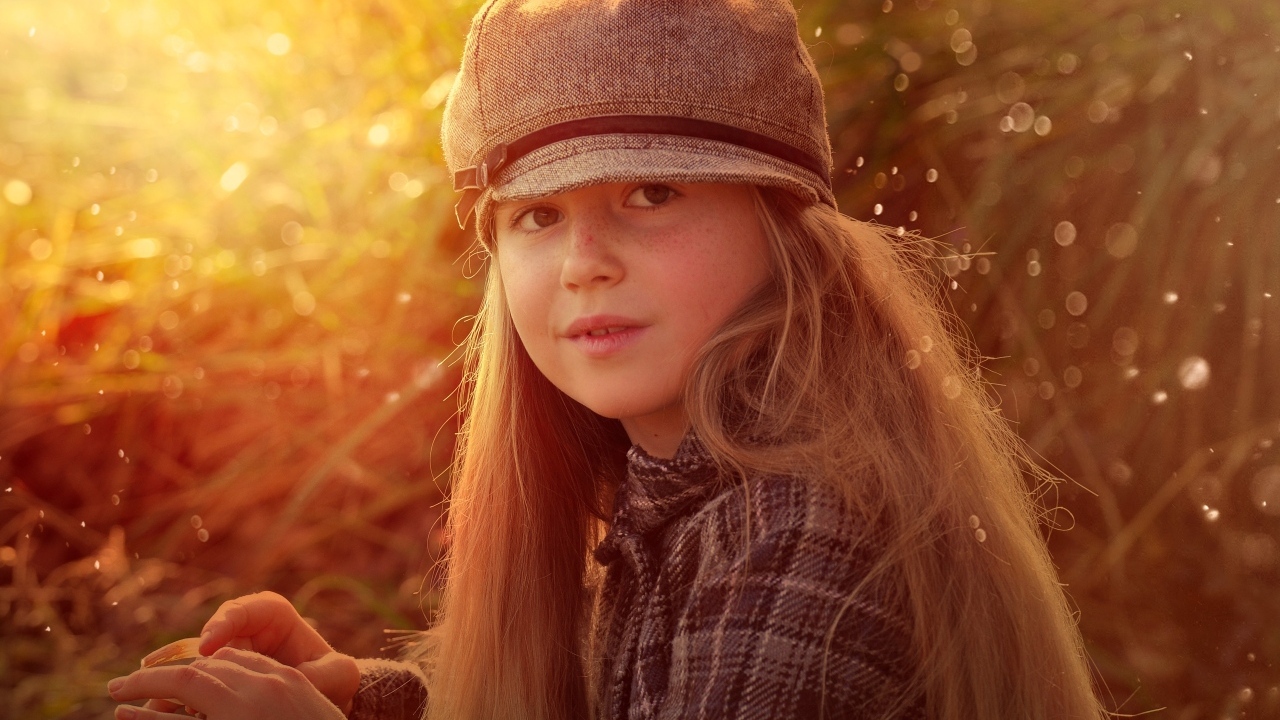 Длинноволосая девочка в кепке в лучах солнца