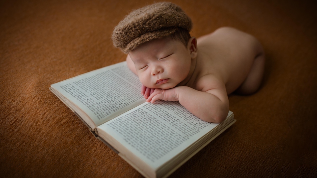 Новорожденный малыш спит на книге