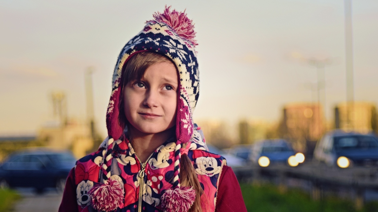 Грустная девочка в теплой шапке на улице