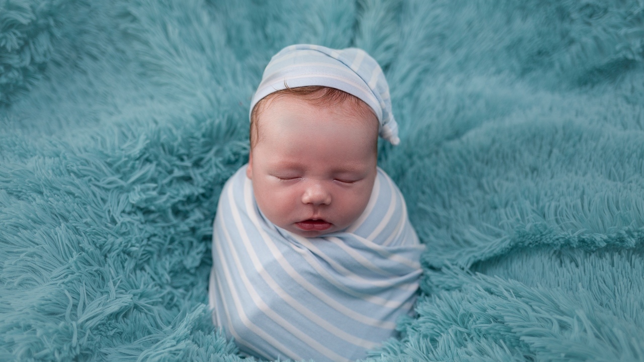 Спящий новорожденный малыш на голубом покрывале 