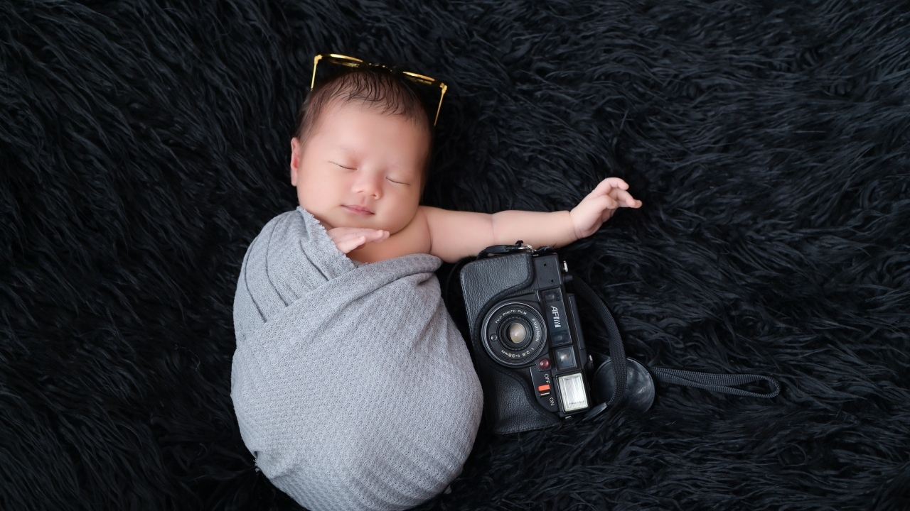Спящий новорожденный малыш с фотоаппаратом