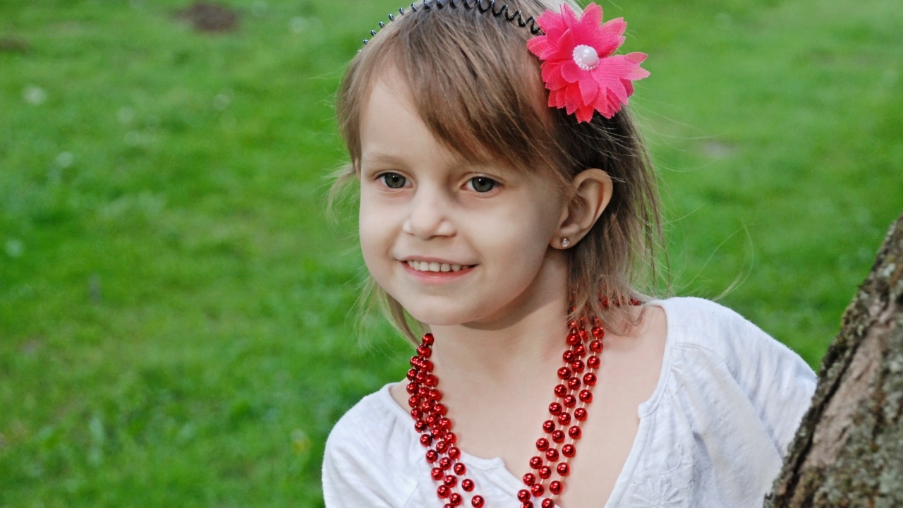 Улыбающаяся девочка стоит у дерева