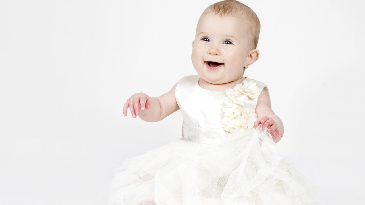 Улыбающаяся маленькая девочка в белом платье 