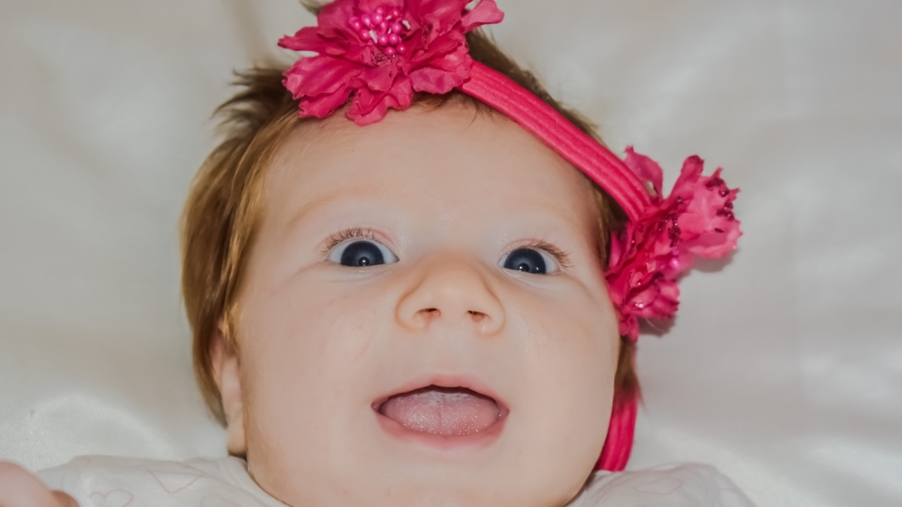 Улыбающаяся маленькая девочка с цветком на голове