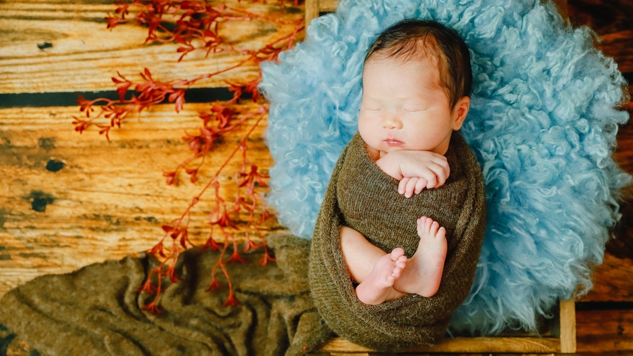 Крошечный новорожденный ребенок на голубой меховой подушке