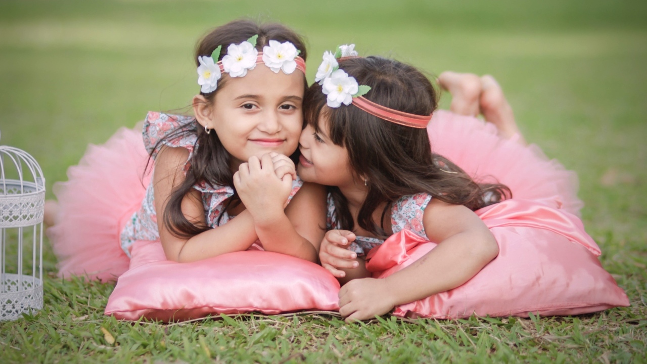 Две маленькие девочки лежат на подушках на траве