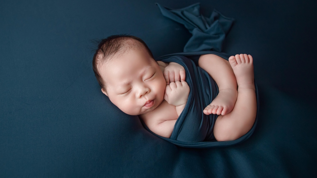 Новорожденный малыш в черном покрывале