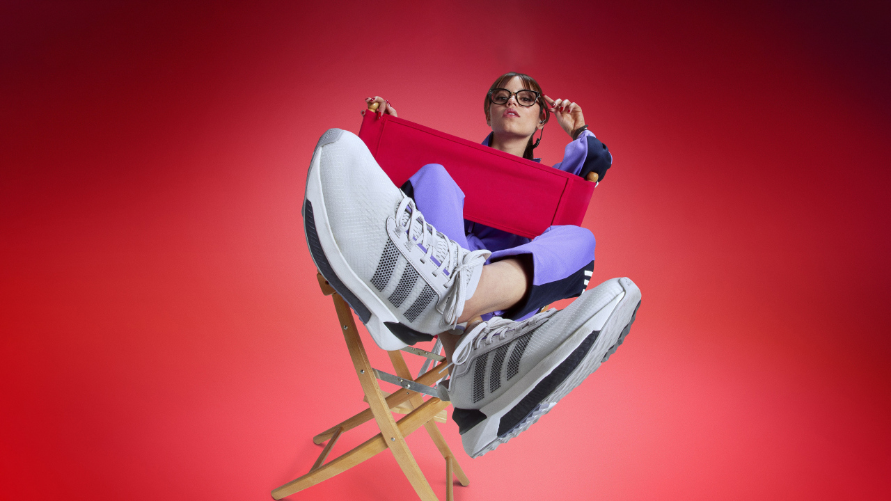 Актриса Дженна Ортега в кроссовках адидас сидит на стуле