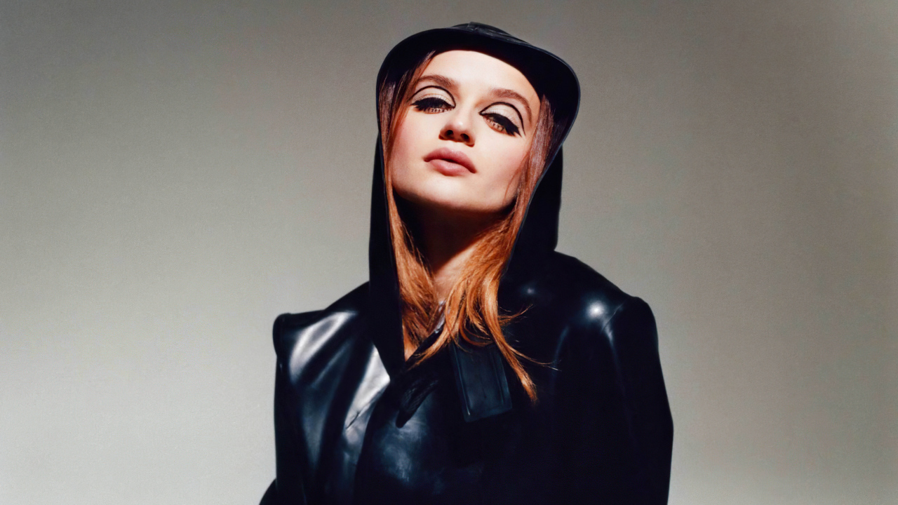 Актриса Джоуи Кинг в черной куртке на сером фоне