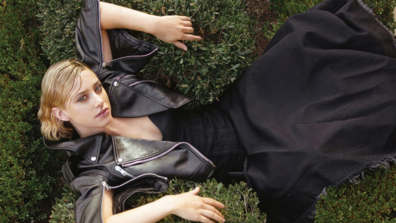 Актриса Лили Рейнхарт в черном костюме лежит в траве