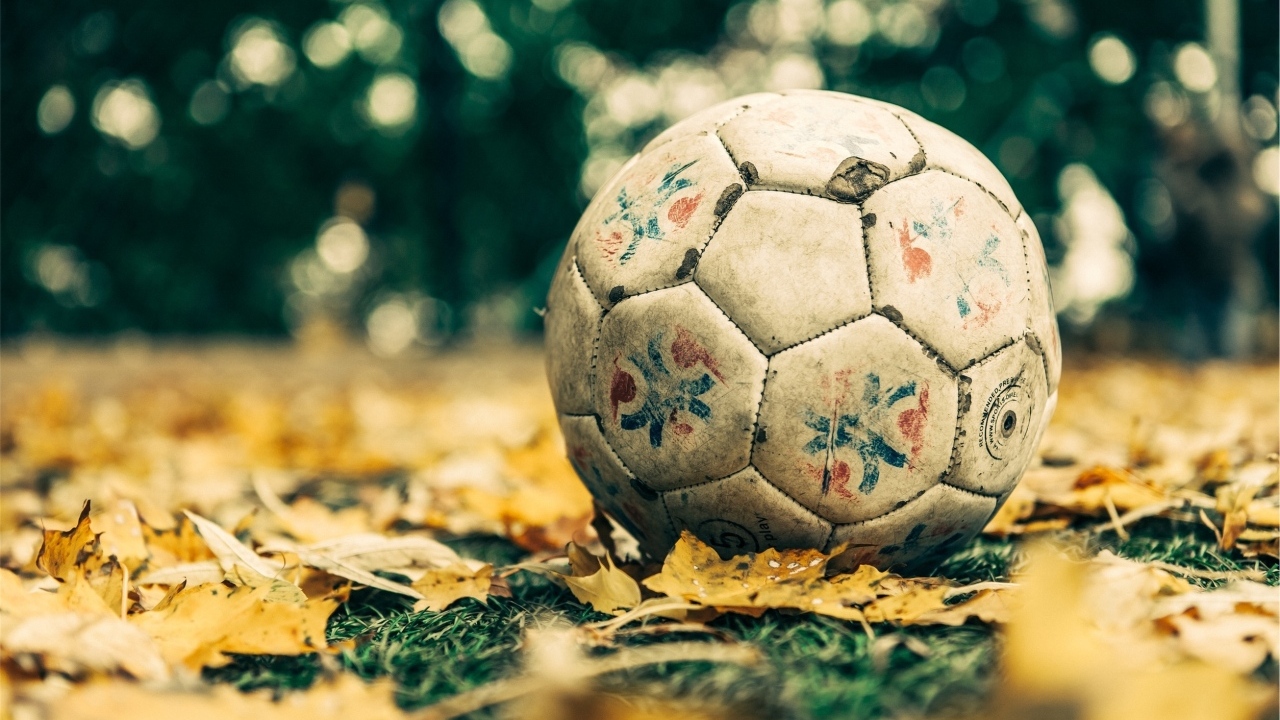 Старый футбольный мяч на листве 