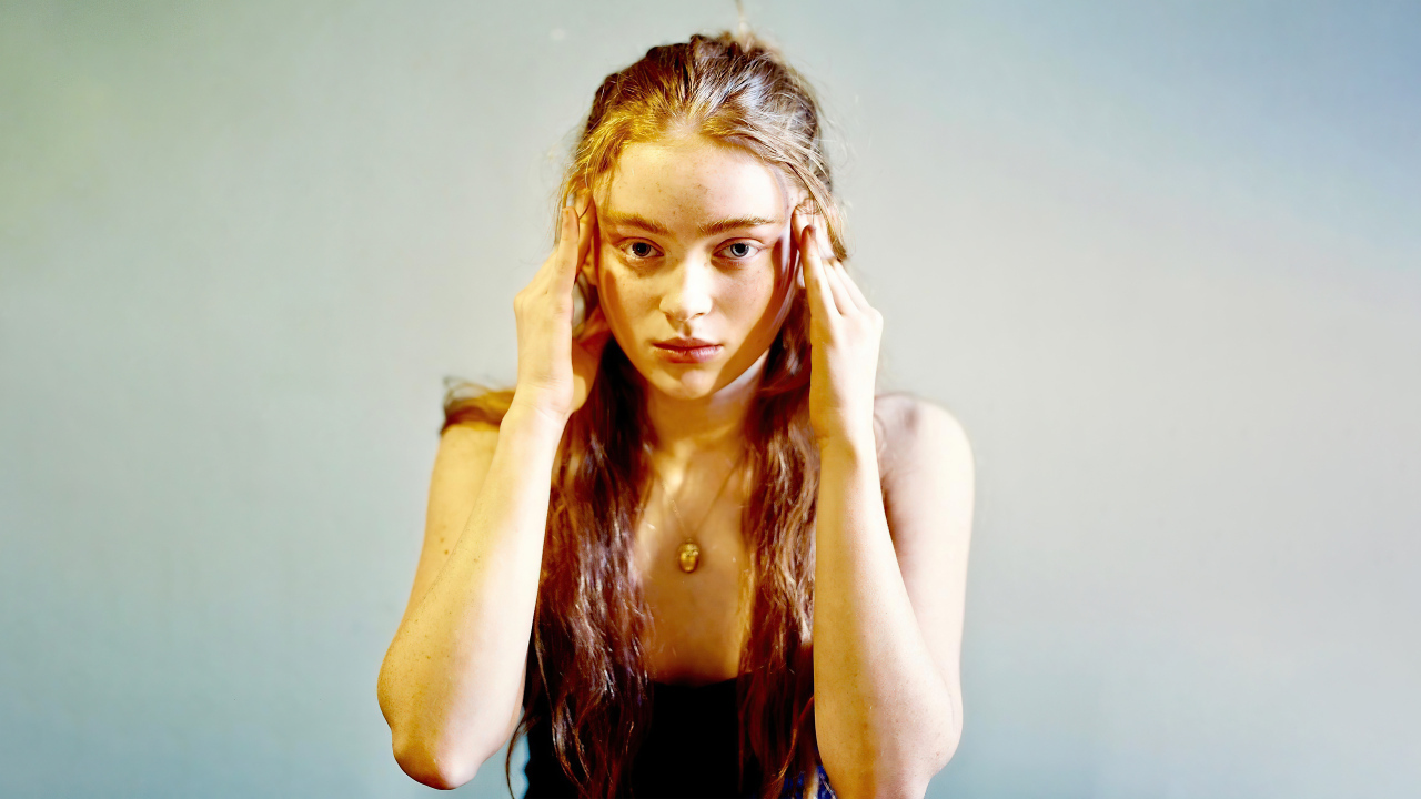 Рыжеволосая американская актриса Сэди Синк на сером фоне