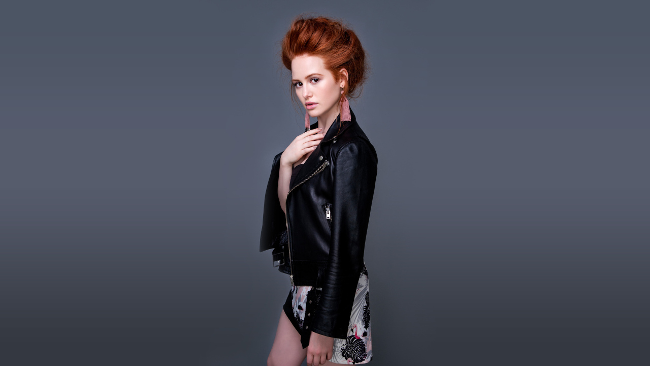 Рыжеволосая актриса Мэделин Петш в черной куртке на сером фоне