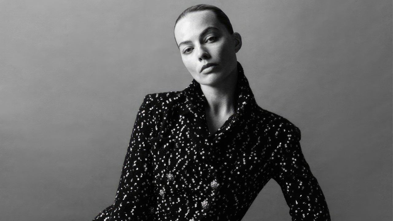 Грустная Марго Робби в блестящем пиджаке на сером фоне