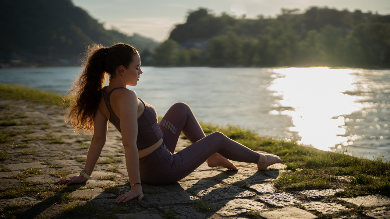 Спортивная девушка сидит на берегу реки