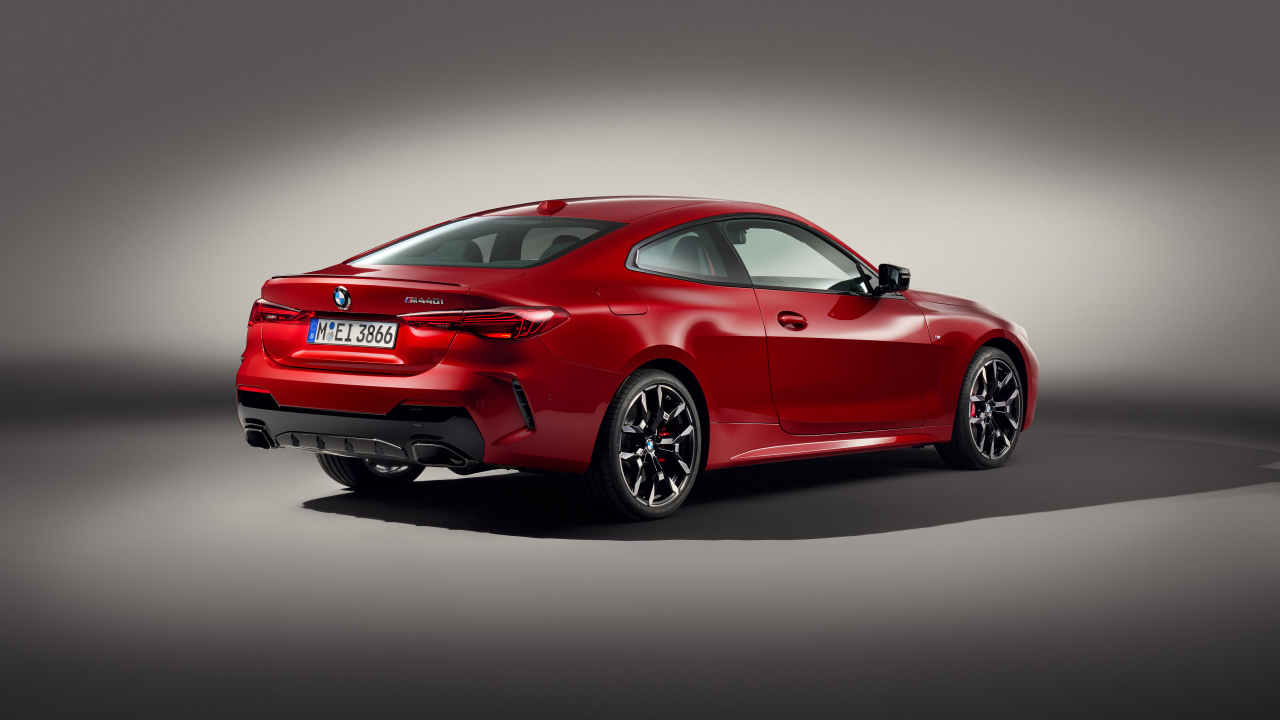 Красный автомобиль BMW M440i XDrive Coupé 2024 года на сером фоне