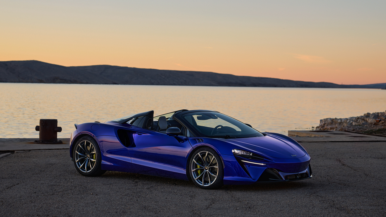 Синий быстрый автомобиль McLaren Artura Spider у воды