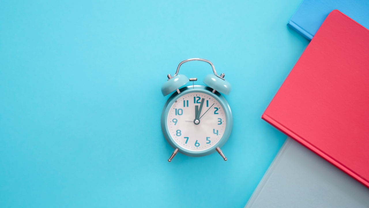 Будильник с книгами на голубом фоне