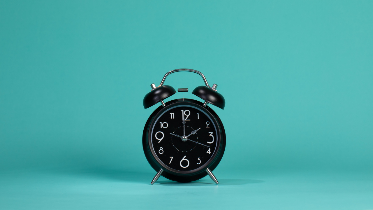 Черный будильник на голубом фоне