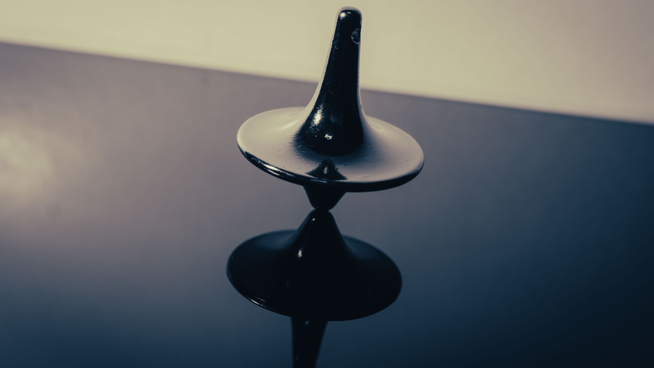 Черный волчок на ровной поверхности