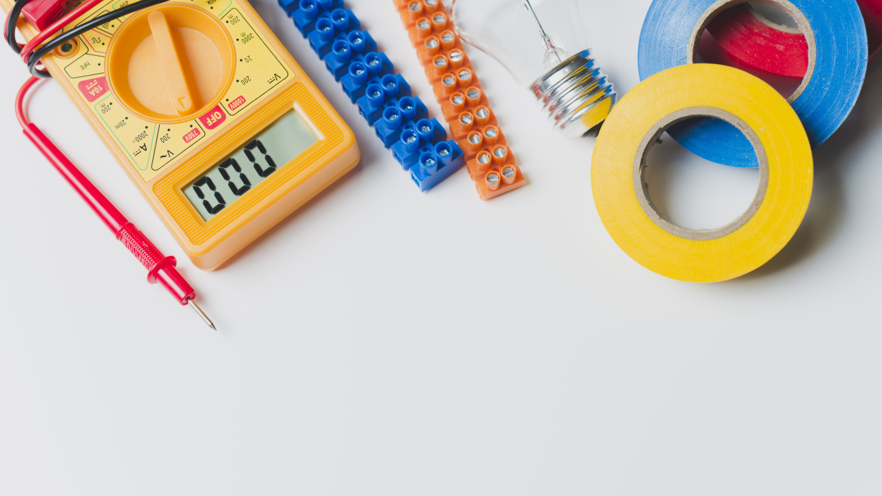 Электрическические приборы, мультиметр, изолента на сером фоне