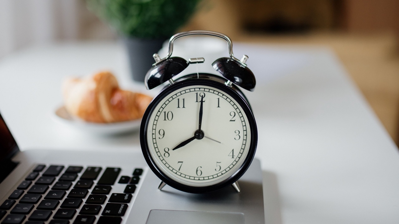 Большой черный будильник на столе у ноутбука