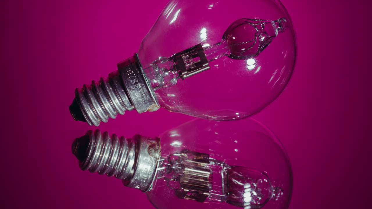 Лампочка отражается в поверхности на сиреневом фоне
