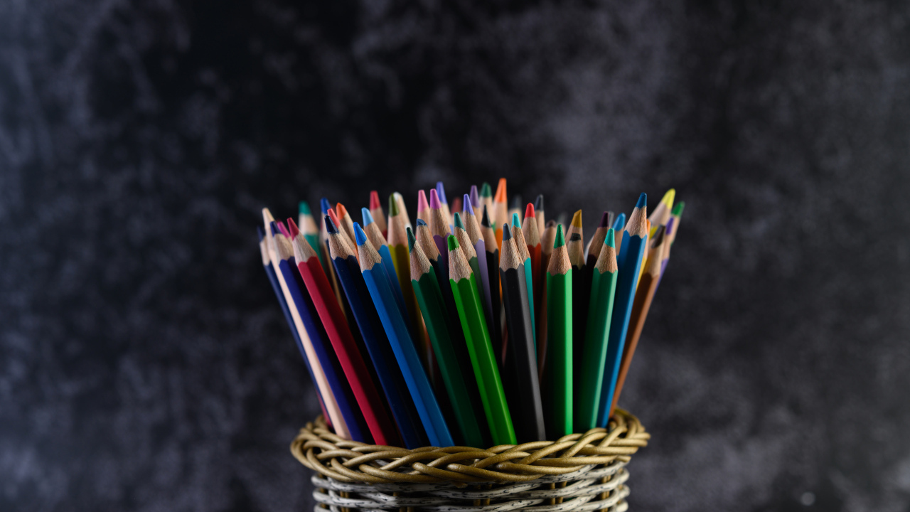 Разноцветные карандаши в стакане на сером фоне