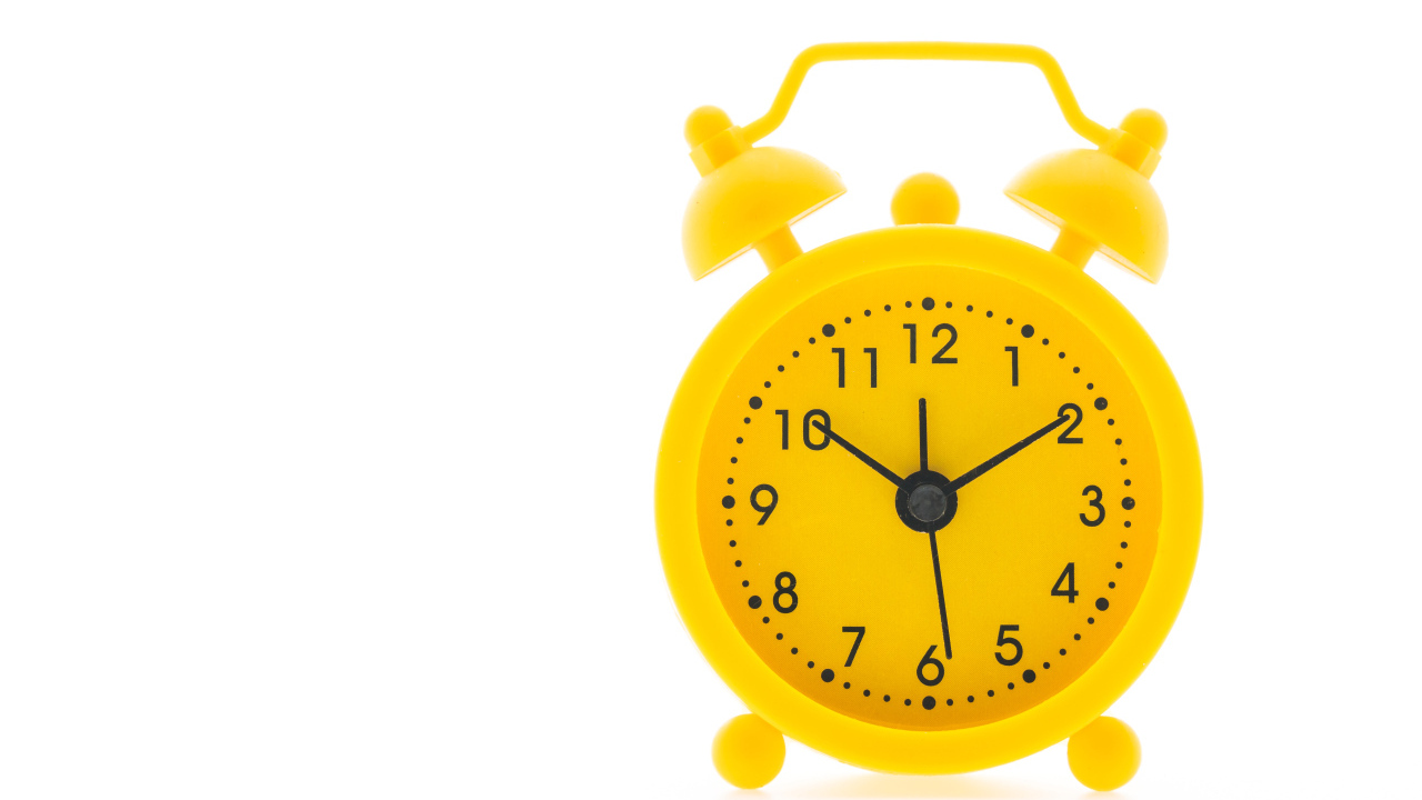 Желтый будильник на белом фоне