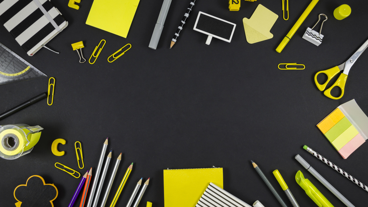 Желтые разные канцелярские предметы на черной поверхности 