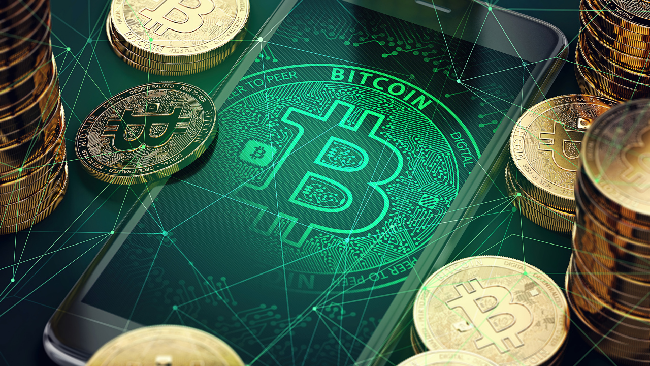 Золотые монеты биткоин со смартфоном на столе