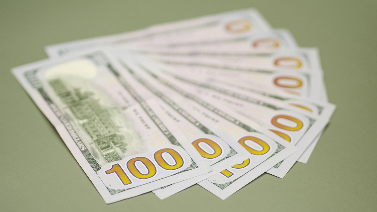 Пачка стодолларовых купюр на зеленом фоне