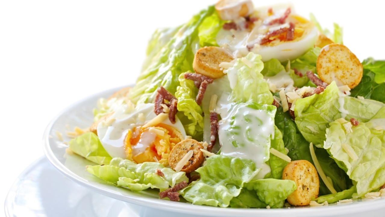 Салат Цезарь на большой белой тарелке