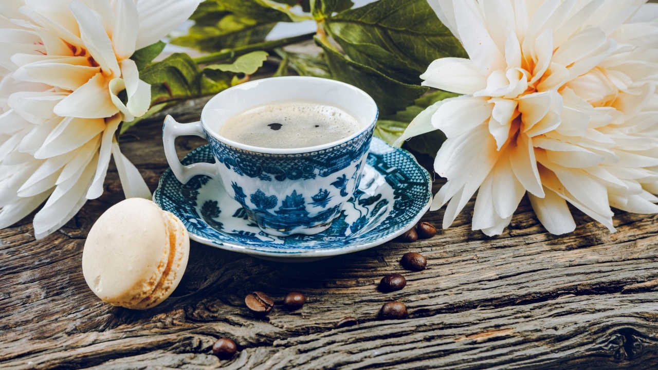 Чашка кофе с макарунами на столе с цветами