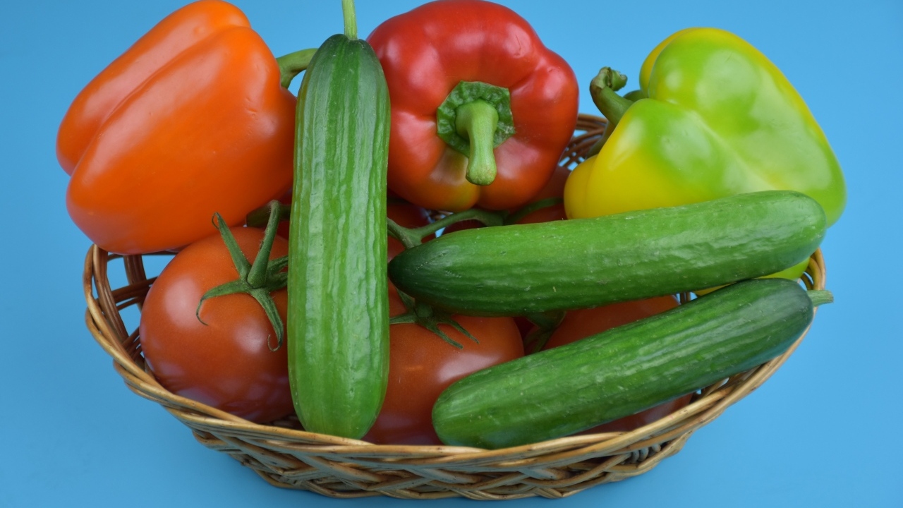 Перец, помидоры и огурцы в корзине на голубом фоне