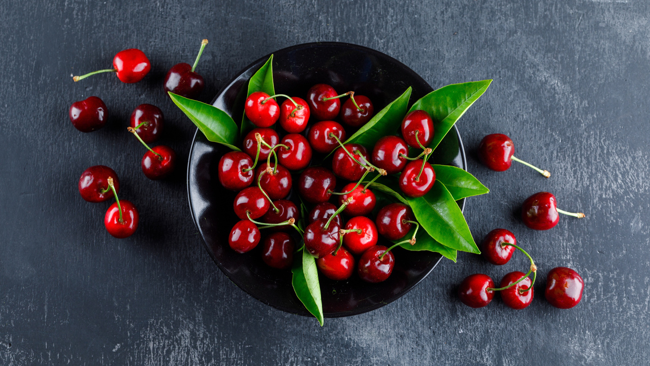 Черная  тарелка с красными ягодами черешни