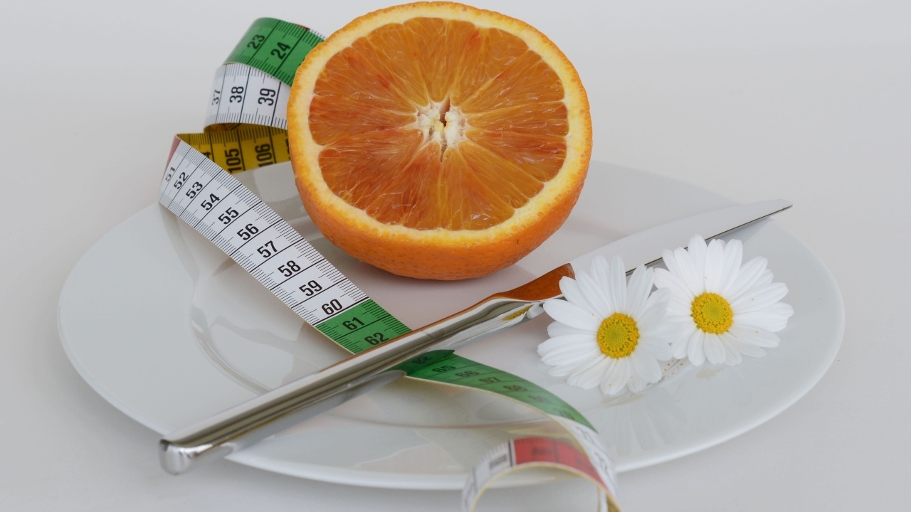 Половина апельсина на тарелке с сантиметром