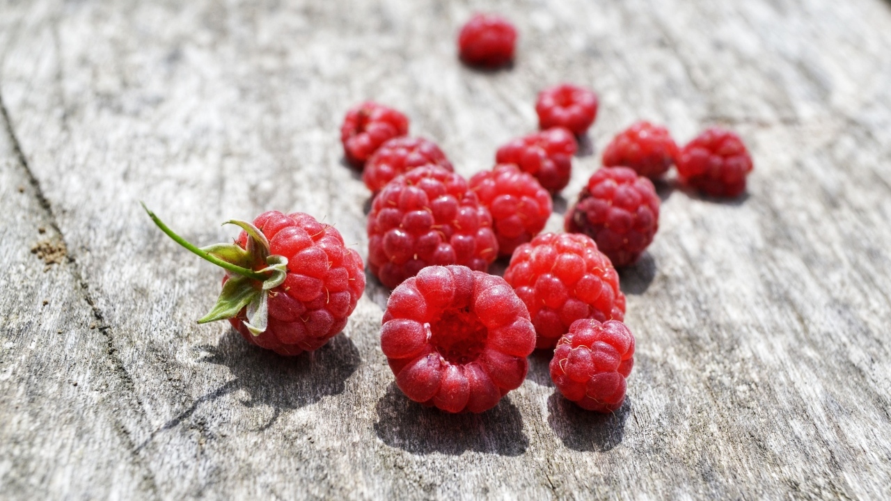 Красные ягоды малины на деревянном столе