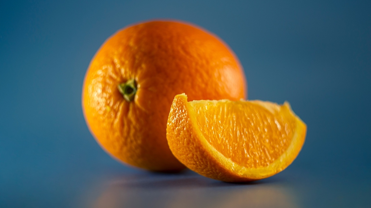 Спелый оранжевый апельсин на голубом фоне