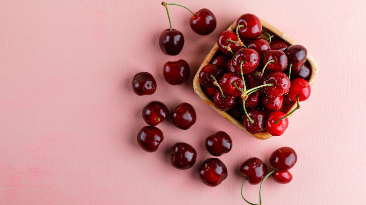 Спелые сладкие красные черешни на розовом фоне