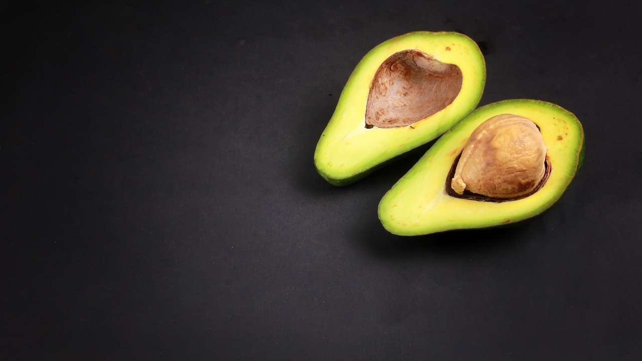 Две половинки зеленого авокадо на сером столе