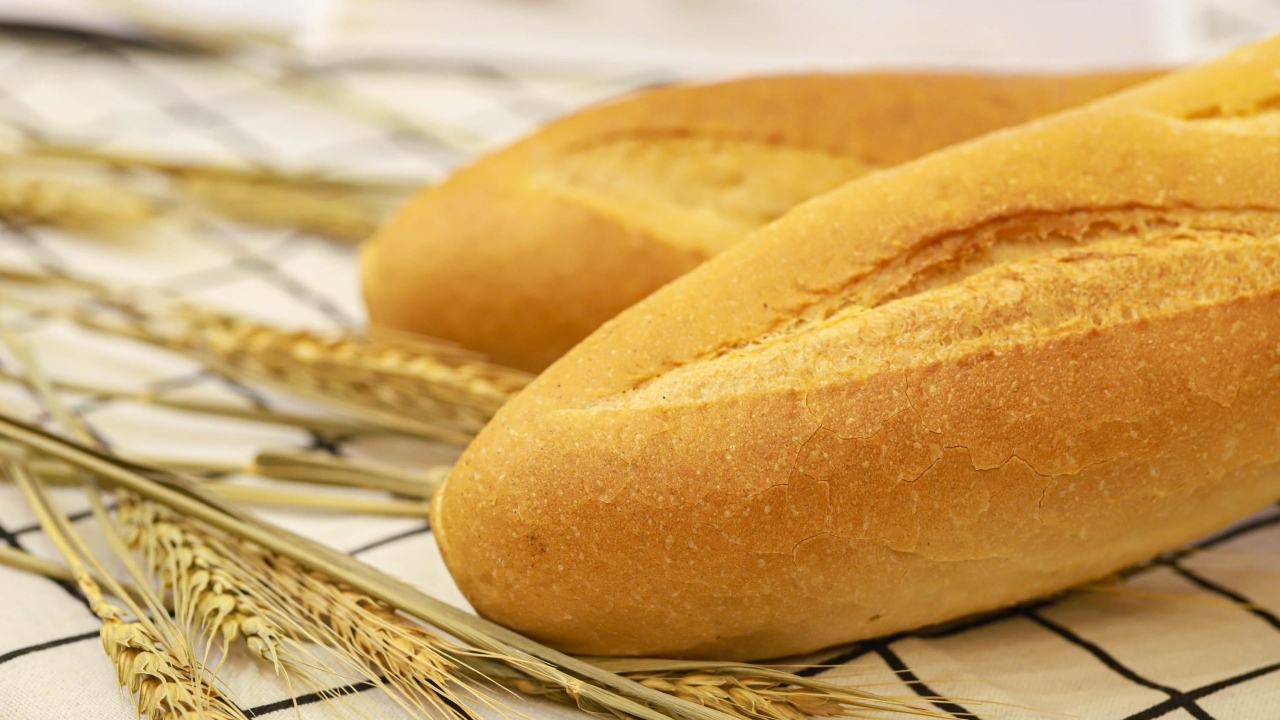 Два батона на столе с колосьями пшеницы