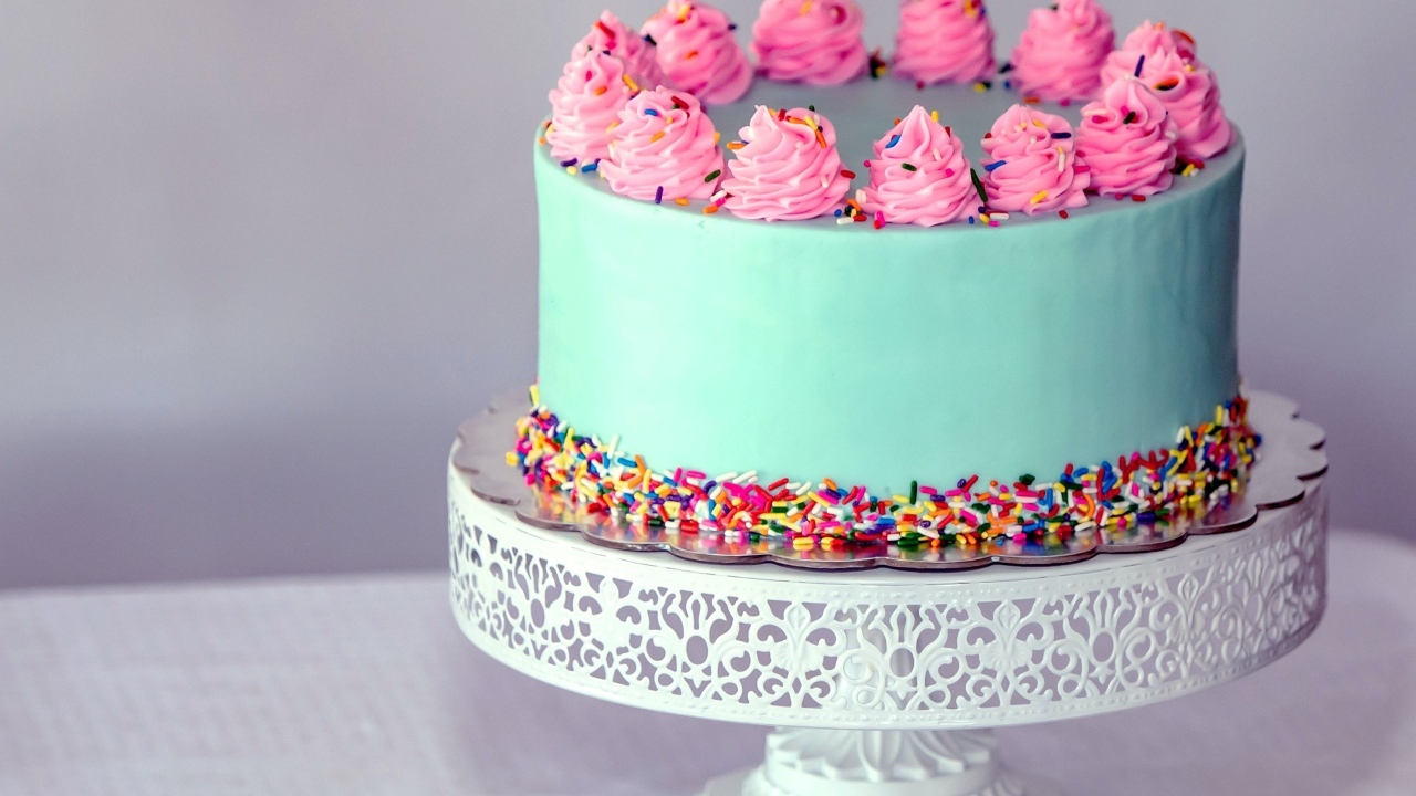 Торт с голубой глазури с розовым кремом на столе